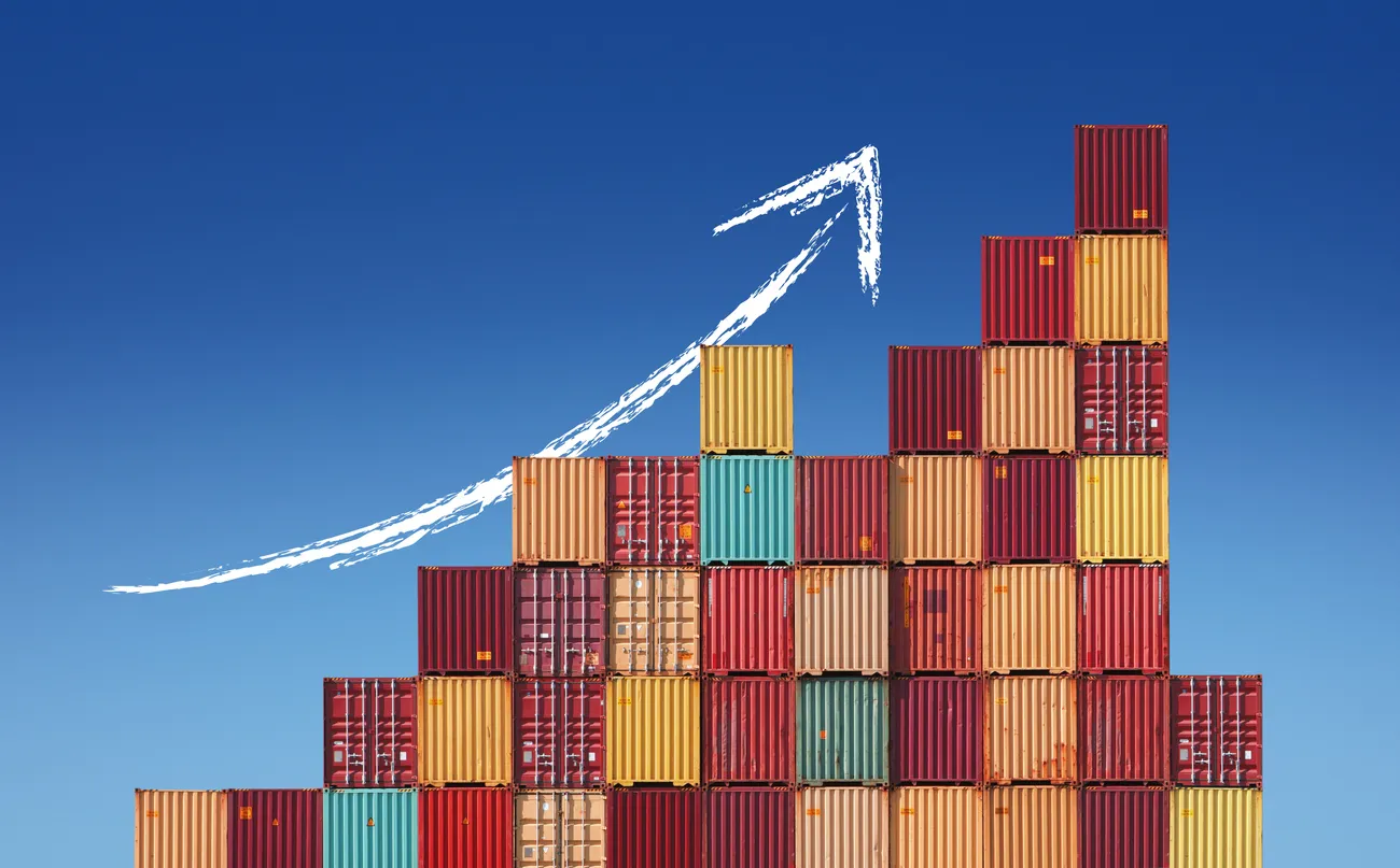 Shipping containers stacked in a rising curve against a blue sky